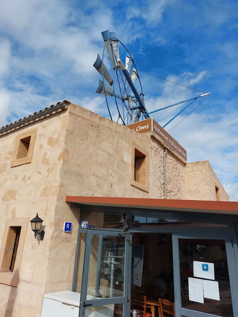Terraza exterior del restaurante Molí de Son Oms con cartel y pared de piedra mallorquina, Son Oms Palma